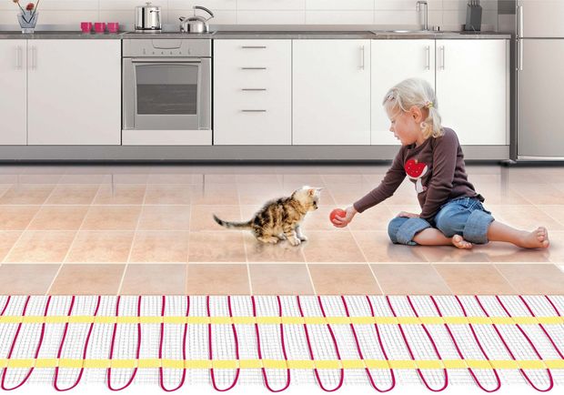 Ребенок играет с котенком на теплом полу